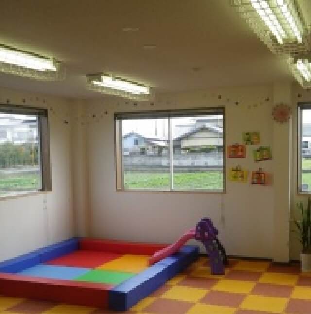写真：障がい児通所の室内の様子。クッションマットが敷かれ、遊び場スペースも設けられている。