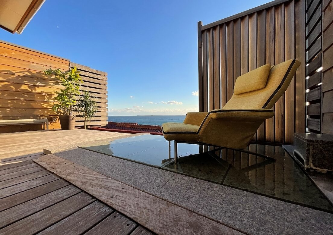 写真：屋外の温泉施設にプルミエを導入した様子。奥には海が広がっている。